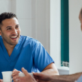 Male medical professional talking to a colleague holding a cup